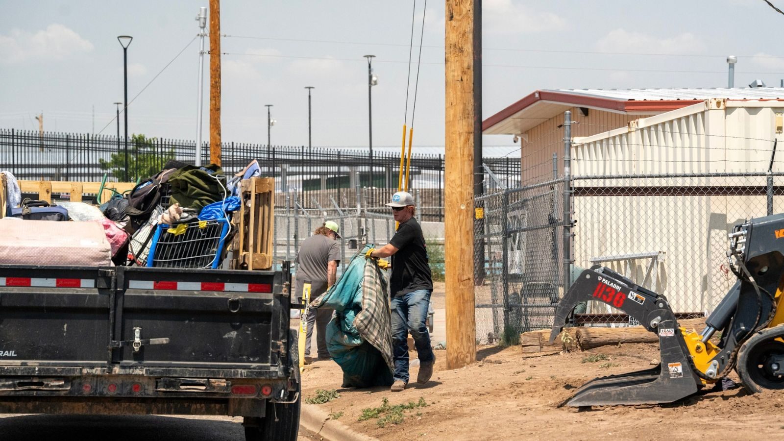 Two men beside a loaded trailer and a loader.
