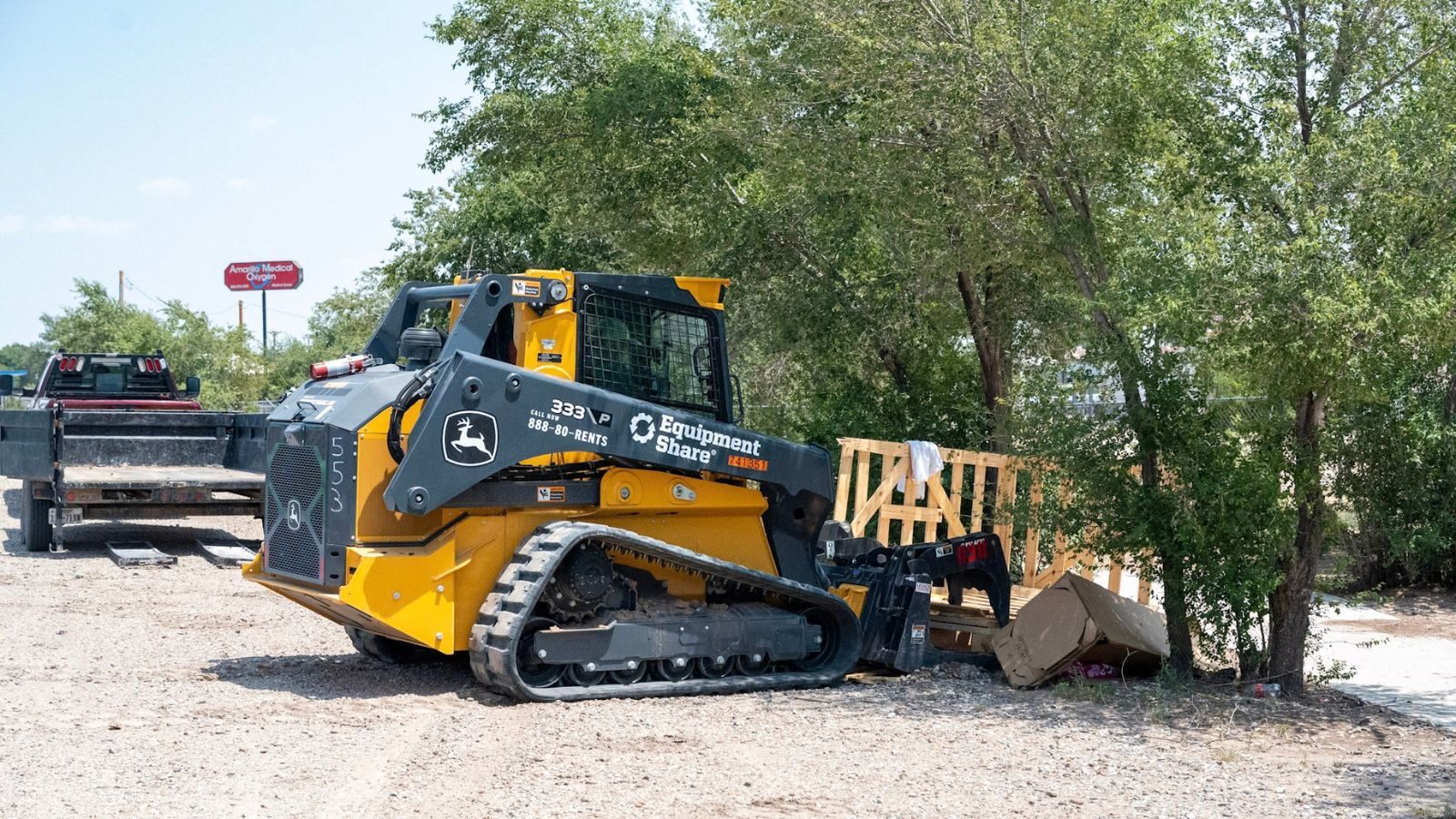 A yellow loader beside wooden pallets and cardboard.